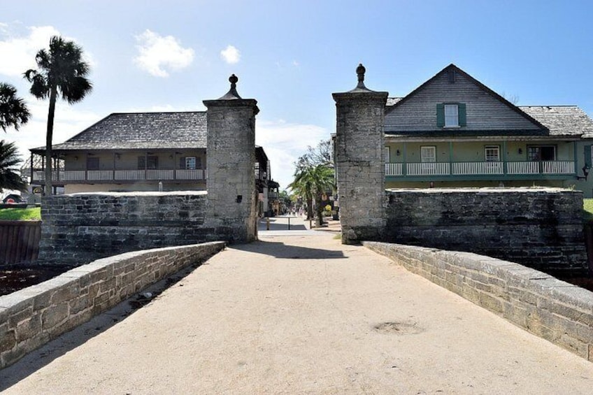 A historic fort entrance with stone walls and a paved path leading through. 2