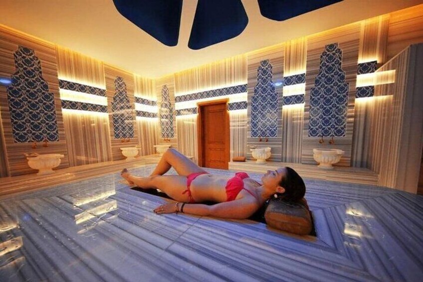 A woman lying on a marble floor in a spa-like setting with patterned walls and decorative lighting. 5