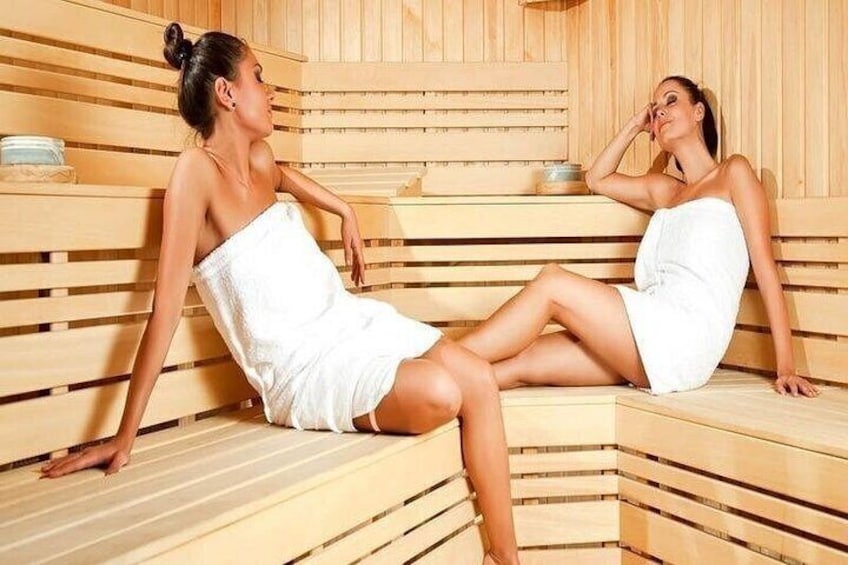 Two people in a sauna with wooden benches and benches. 3