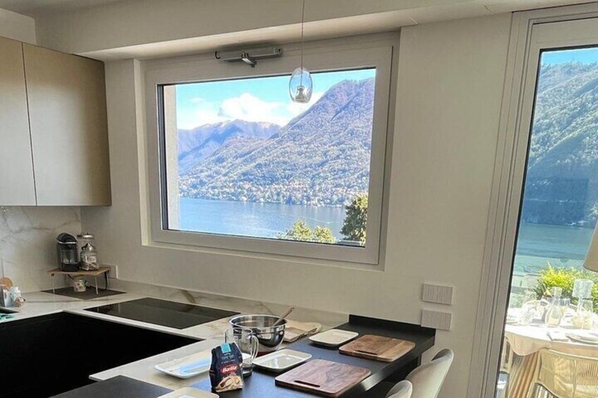 Eine Küche mit großem Fenster und Blick auf einen Bergsee. 1