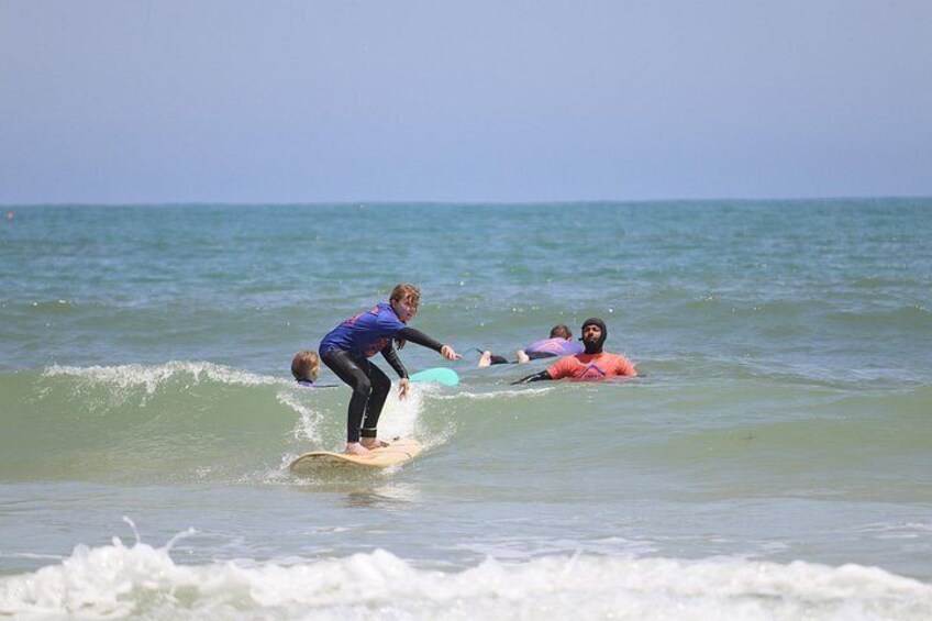 Eine Person surft auf einer Welle, eine andere Person liegt auf einem Surfbrett und ein dritter Mensch schwimmt im Meer. 5
