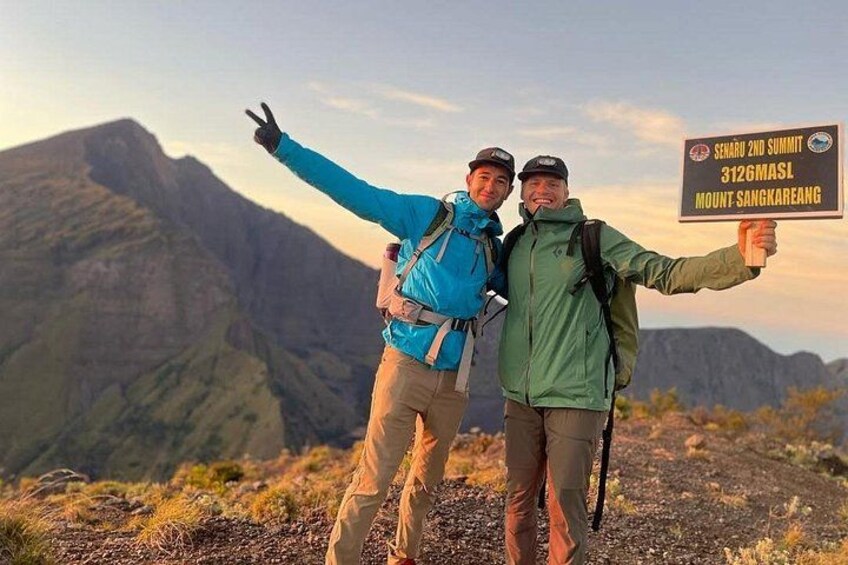 Twee wandelaars bij een bord met daarop de locatie van Mount Sangkareang. 1
