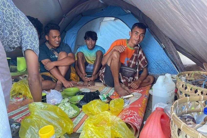 Een groep mensen zit in een tent, met verschillende spullen verspreid rondom. 4