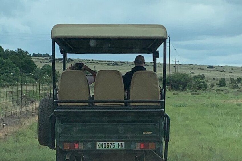 A vehicle with two passengers in a rural setting. 1