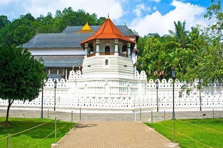 Ein weißer Tempel mit rotem Dach, umgeben von einem weißen Zaun und Grünpflanzen. 5
