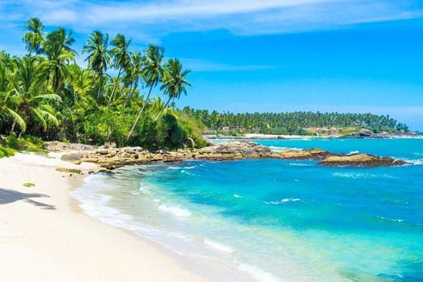Ein Strand mit klarem türkisblauem Wasser, weißem Sand und Palmen. 2