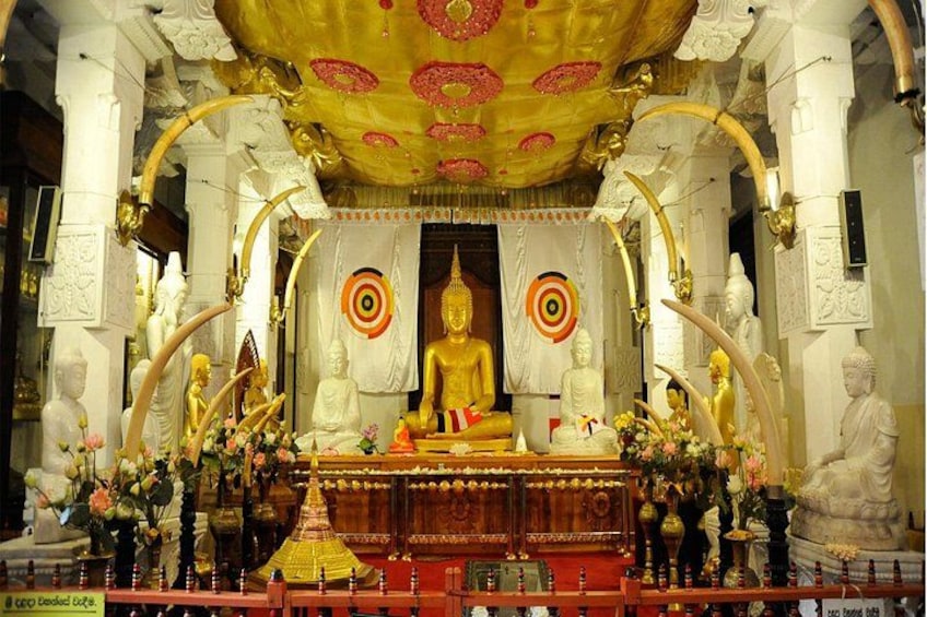Eine goldene Buddha-Statue in einem Tempel mit aufwendiger Architektur und zahlreichen kleineren Statuen. 4