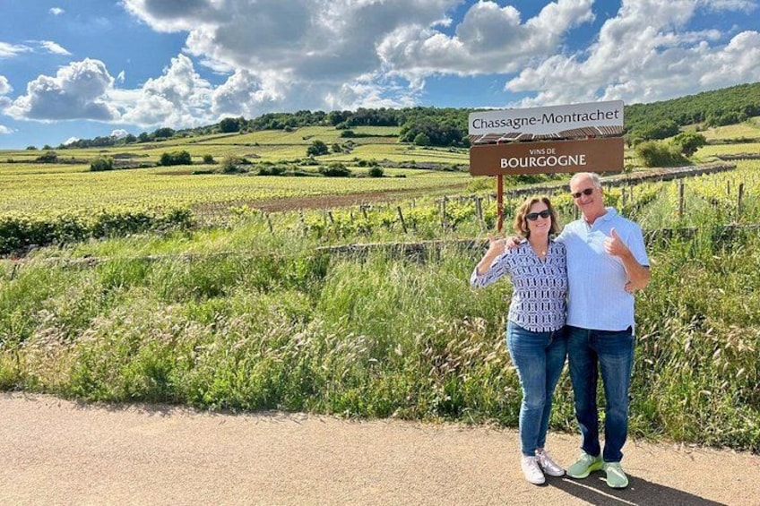Een landelijk landschap met een bord waarop 'Chassagne-Montrachet' en 'Vins de Bourgogne' staan. 3