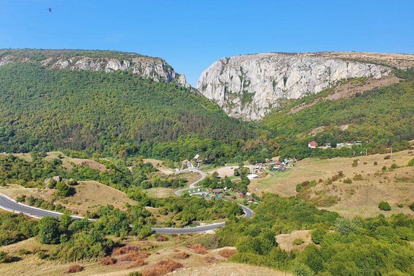 Une route sinueuse traverse une vallée, avec un village et des falaises en arrière-plan. 4