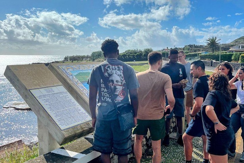 Un grupo de personas de pie junto a un tablón informativo grande cerca de un cuerpo de agua. 3