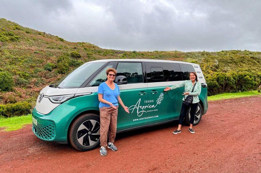 Et grønt køretøj med 'Tours Africa' skrevet på siden holder parkeret på en jordvej med et bakket landskab i baggrunden. 2