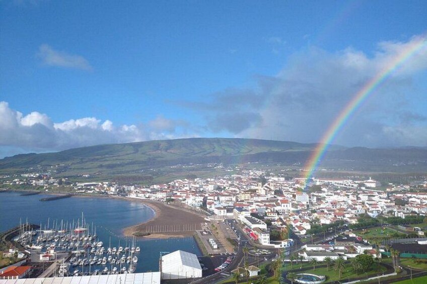 Une ville côtière dotée d’un port de plaisance, où l’on peut admirer un arc-en-ciel, avec des montagnes en toile de fond. 5