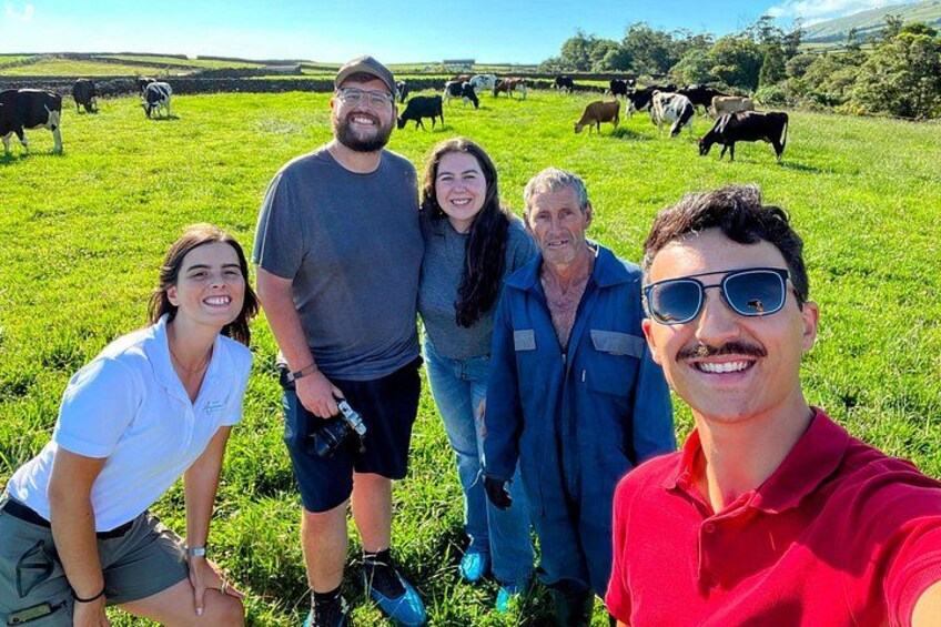 Un groupe de personnes se trouve dans un champ herbeux, avec des vaches en arrière-plan. 2