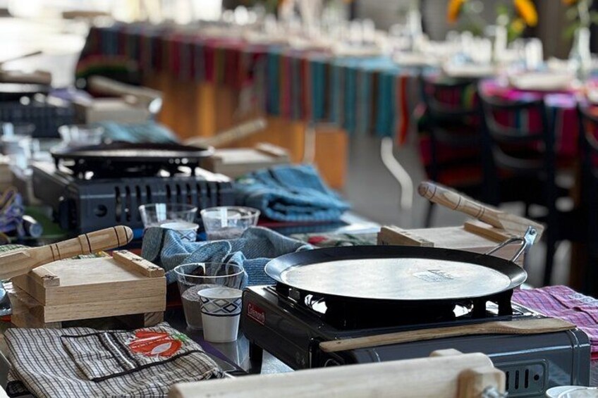Un puesto de mercado con utensilios de cocina, incluyendo una sartén, tablas de cortar de madera y recipientes de plástico. 1