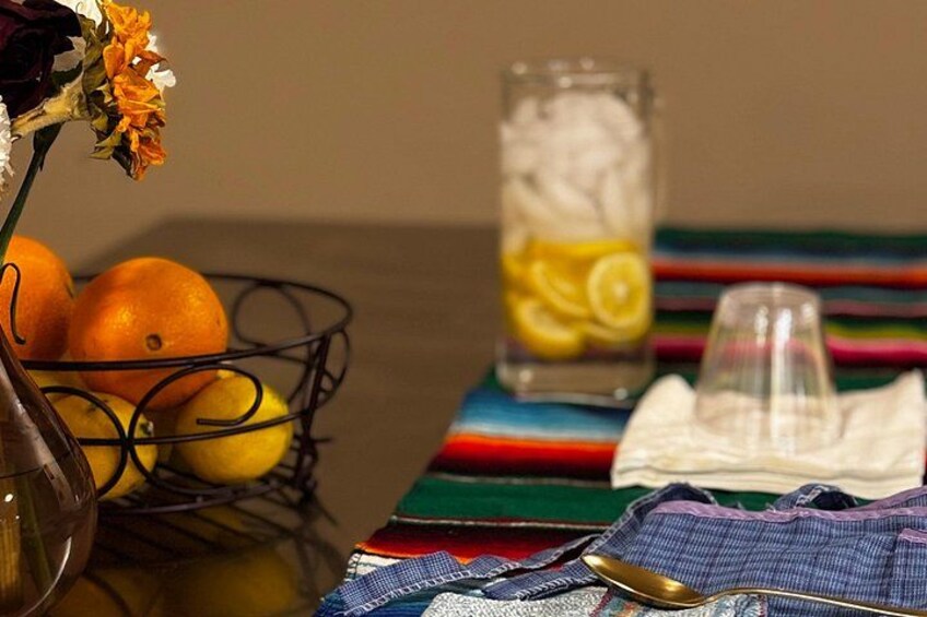 Un tavolo con un vaso di fiori, un bicchiere d'acqua e fettine di limone, arance e un cucchiaio. 2