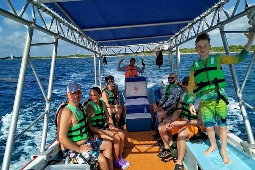 Eine Gruppe von Menschen auf einem Boot mit Metallgestell und blauem Verdeck. 2