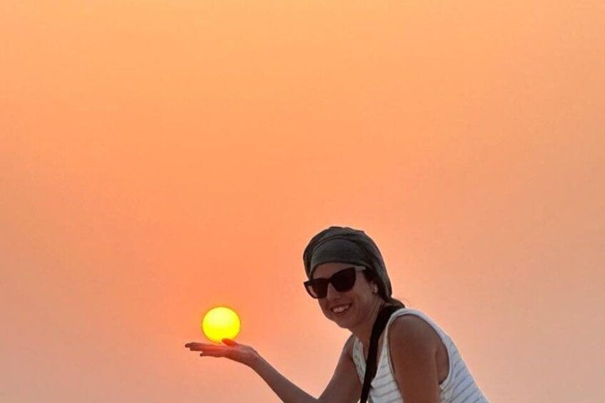 A person holding a glowing orb against a sunset sky. 3