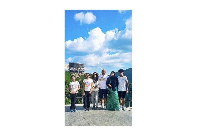 A group of people standing on a concrete platform with a historic building and mountains in the background. 5