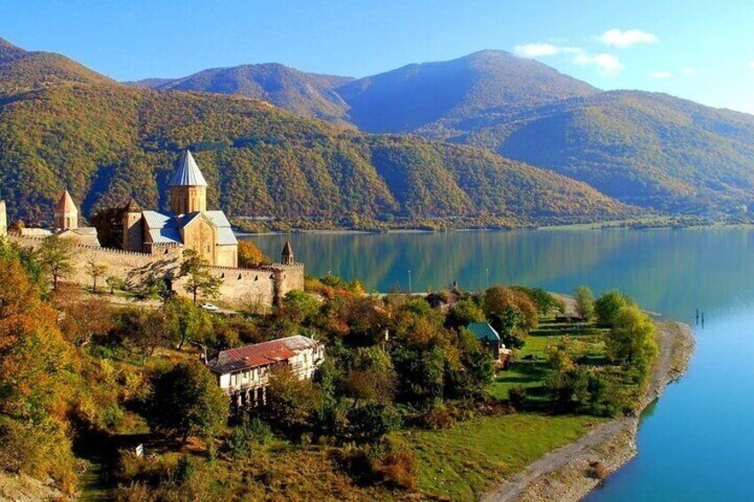 A historic castle by a lake surrounded by mountains. 1
