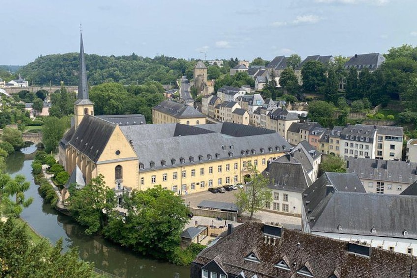A river flowing through a town with historic buildings, a prominent church with a tall spire, and a bridge in the background. 3