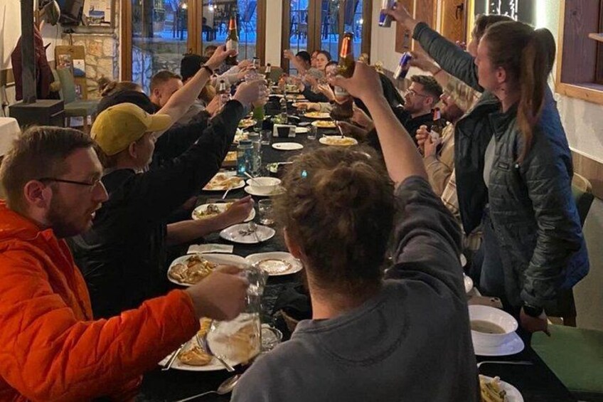 Un grupo de personas sentadas alrededor de una mesa larga, comiendo y brindando con bebidas. 4