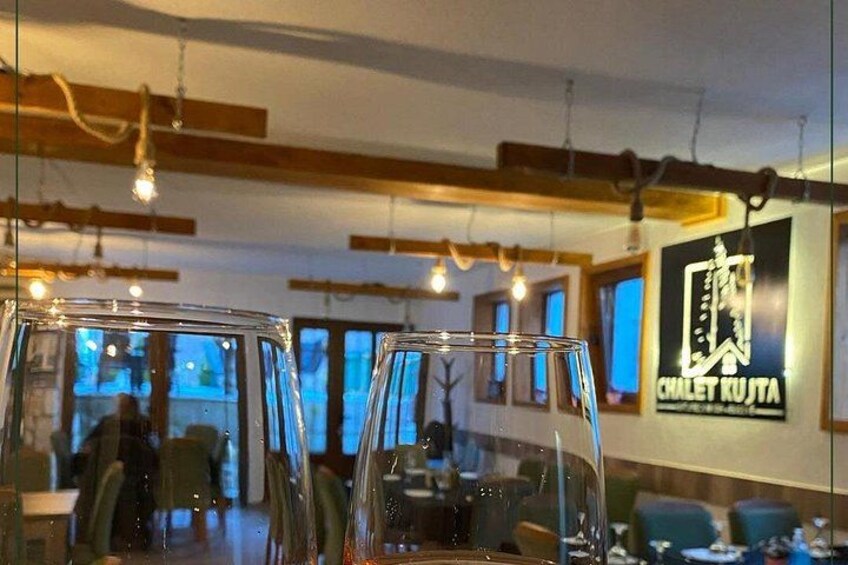 Interior de un restaurante con luces colgantes, mesas, sillas y un letrero que dice 'CHALET KUJTA'. 3