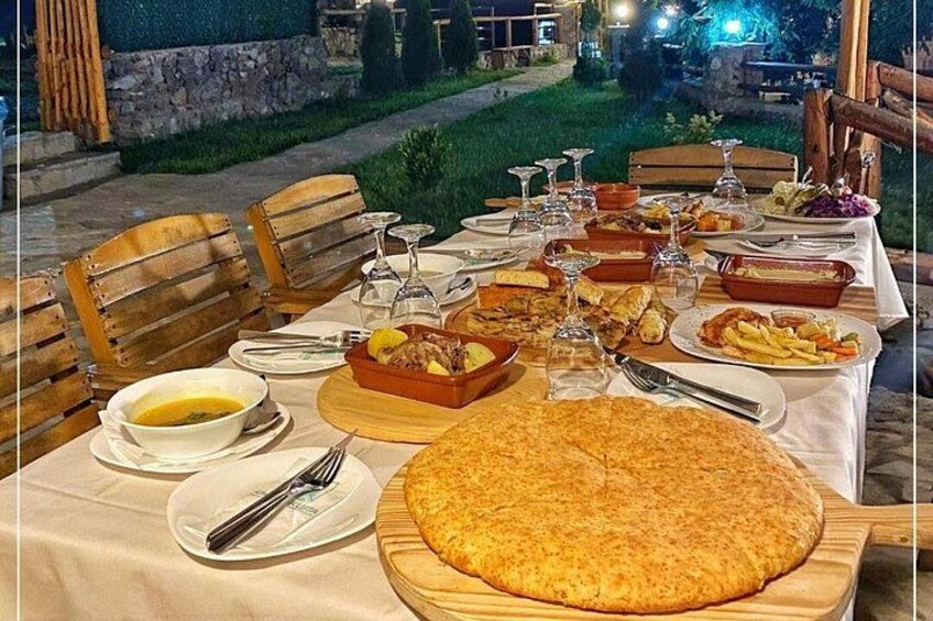 Mesa de comedor exterior con diferentes platos, vasos y sillas de madera. 5