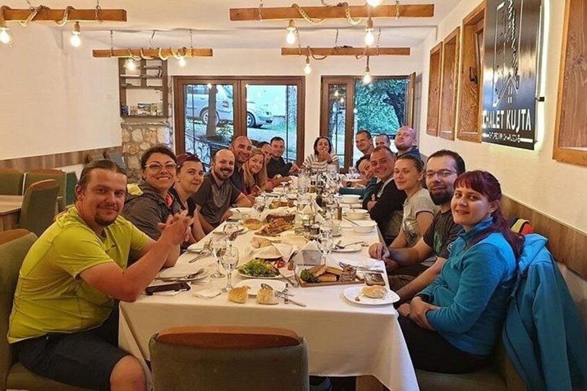 Un grupo de personas sentadas alrededor de una larga mesa en un restaurante con vistas al exterior. 1