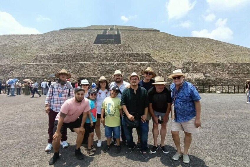 Un grupo de personas posando frente a una gran estructura en forma de pirámide. 1