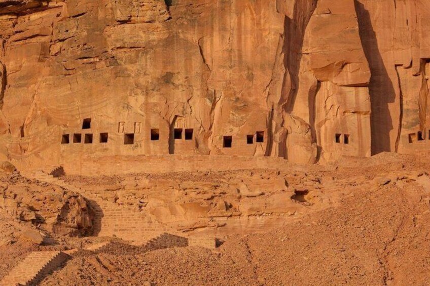 A desert landscape with rock formations and several small cave-like structures. 3