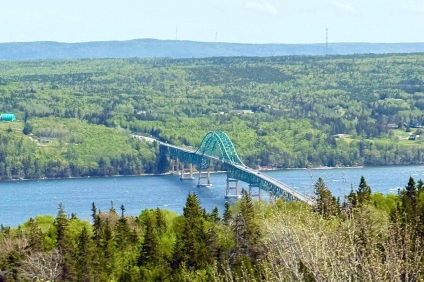 A green bridge over a river, surrounded by dense forest and hills. 4