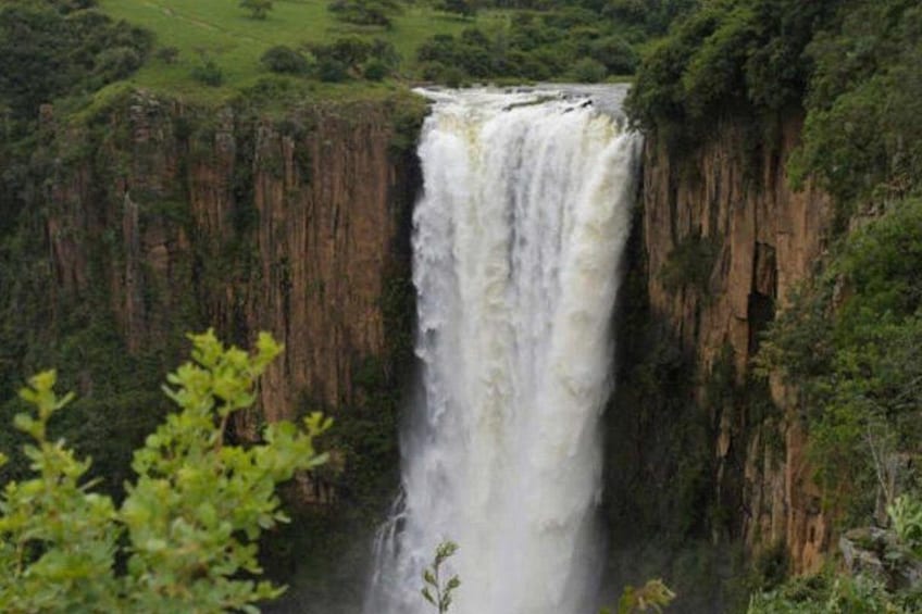 A waterfall cascading down a steep cliff surrounded by lush greenery. 3