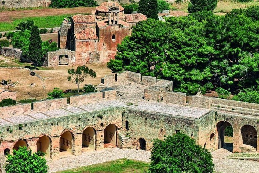 An ancient fortified complex with stone buildings and arched walkways. 2