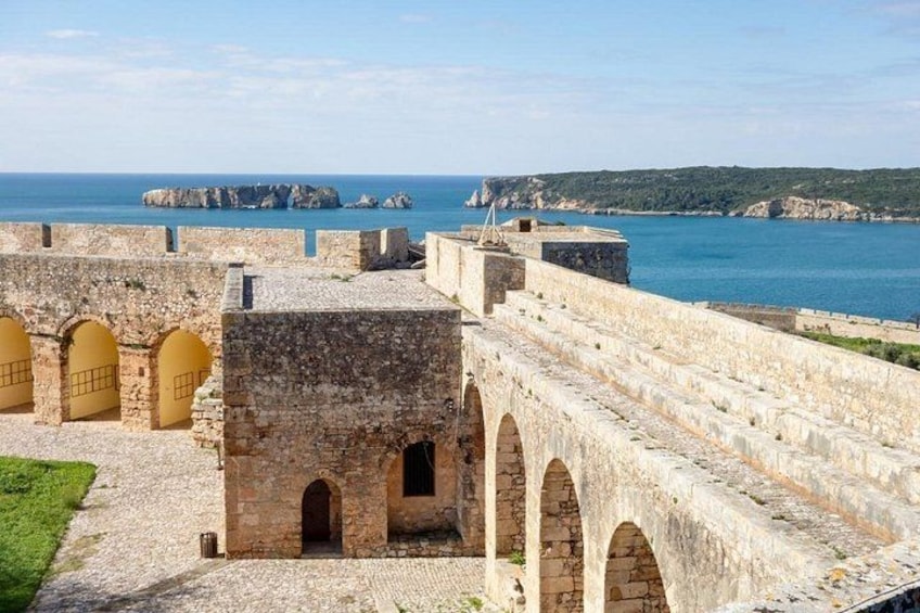 A stone fortification with arched passageways and a view of the sea. 3