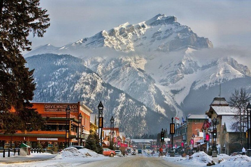 A snow-covered mountain, a town with buildings, and a road. 4