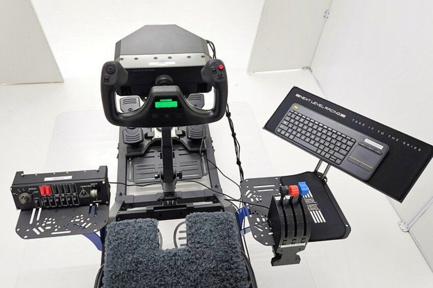 A flight simulator setup with a steering wheel, pedals, and a monitor displaying a keyboard. 5