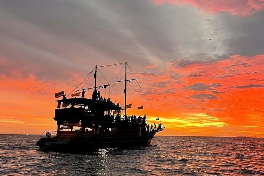 Una barca con più ponti e persone a bordo che naviga sull'acqua al tramonto. 1