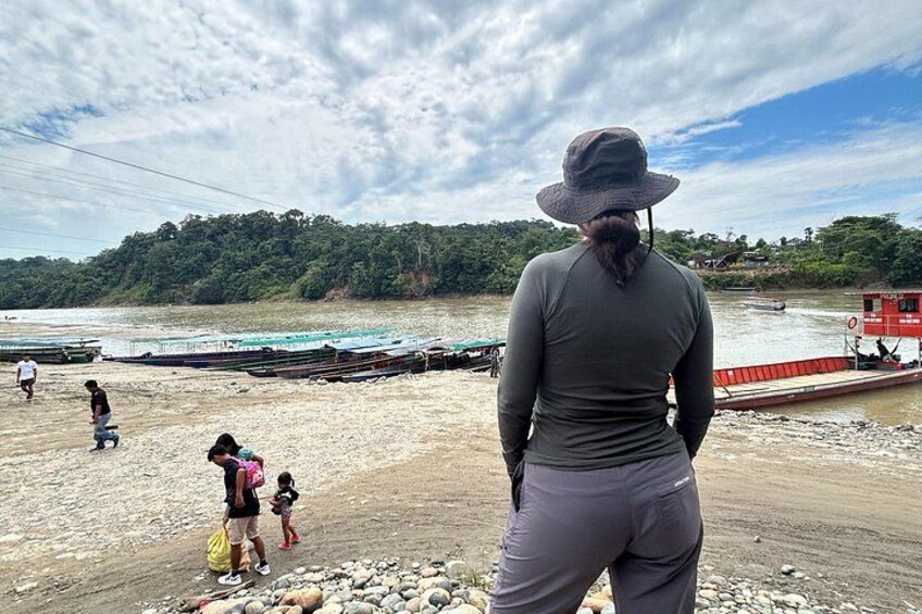 A beach with people, boats, and a forested area in the background. 2