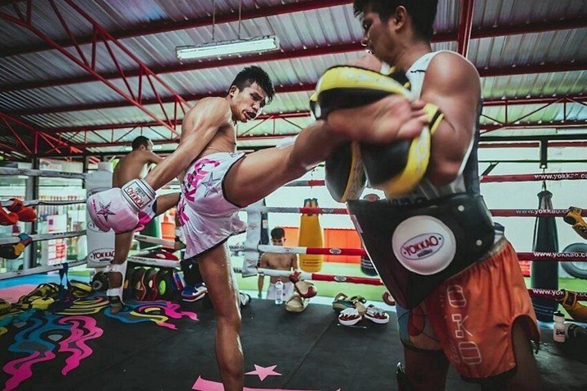 A person practicing martial arts in a gym with boxing equipment and mats. 5