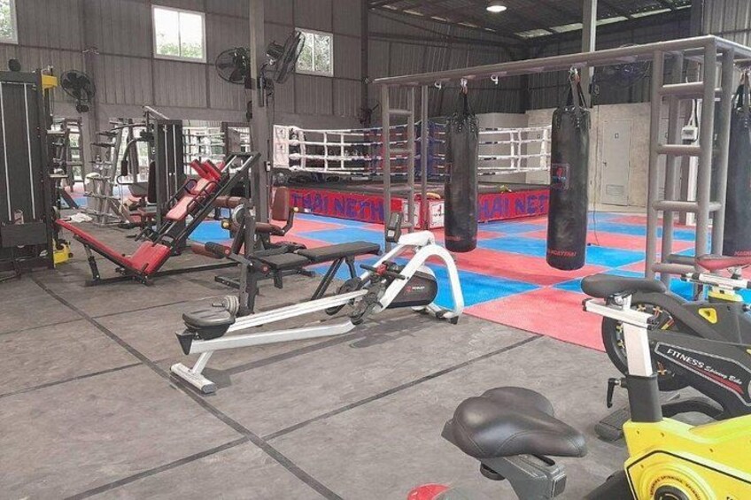 A gym with exercise equipment, punching bags, and a red and blue mat floor. 4
