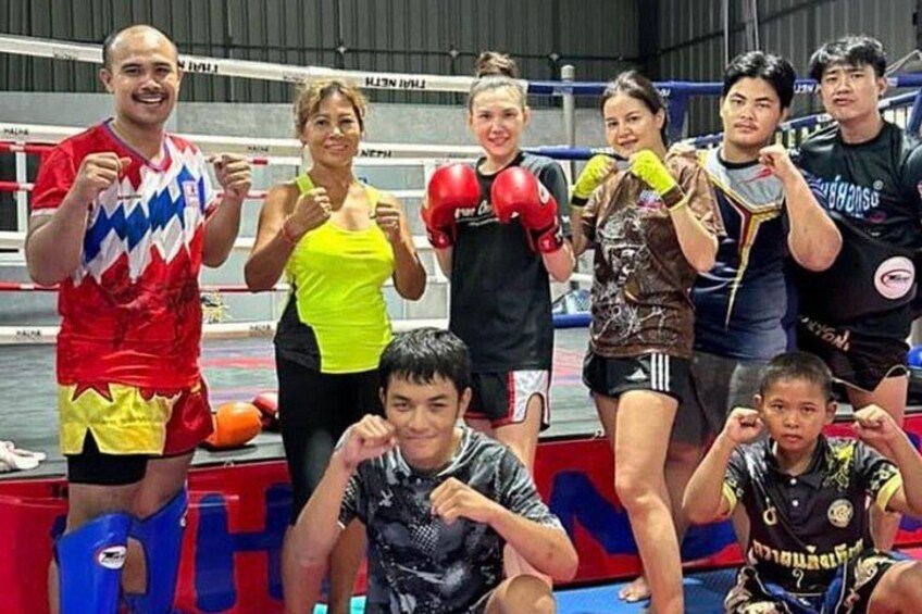 A group of people in a boxing ring, some wearing boxing gloves and others in casual clothing. 1