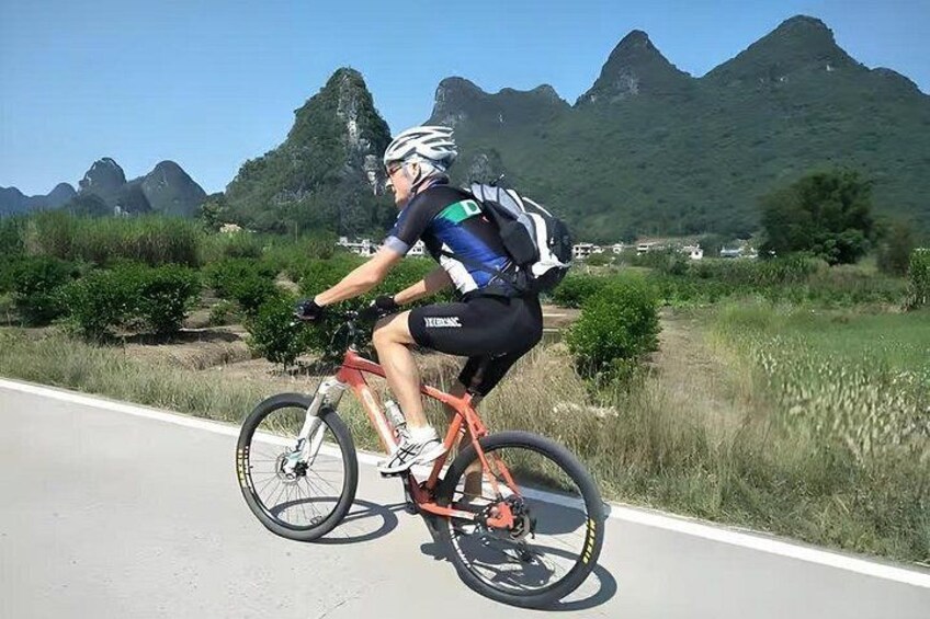 En cyklist på en vej med et bjergrigt landskab i baggrunden. 3
