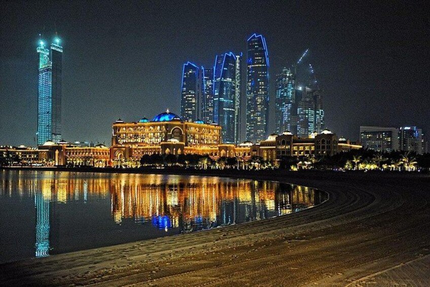 Lo skyline di una città di notte, con edifici illuminati che si riflettono sull'acqua. 3