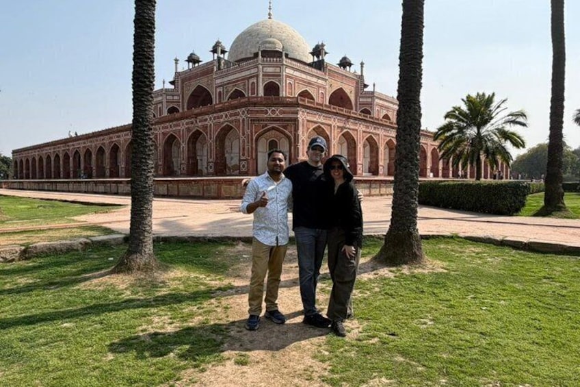 A historical building with domes and arches, palm trees, and a clear sky. 3