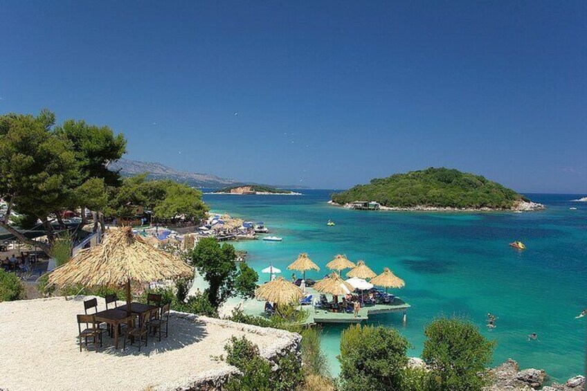 A beach with thatched umbrellas, a boat, and a small island in the background. 5