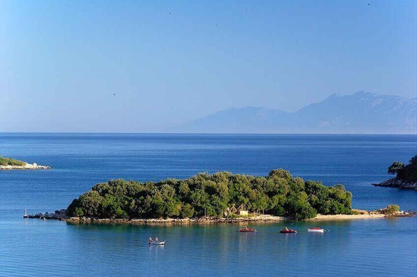 A small island with dense green vegetation surrounded by calm blue waters. 4