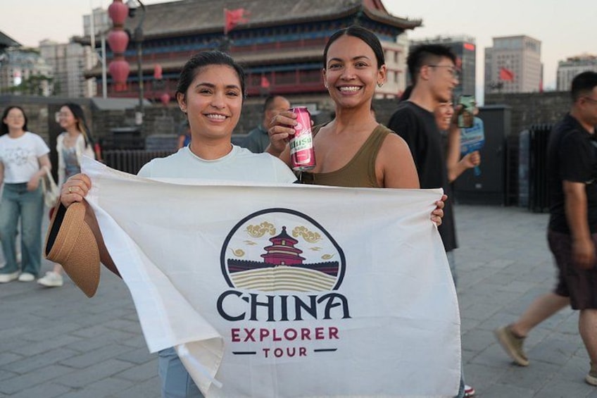 Two people holding a flag with 'CHINA EXPLORER TOUR' text. 1