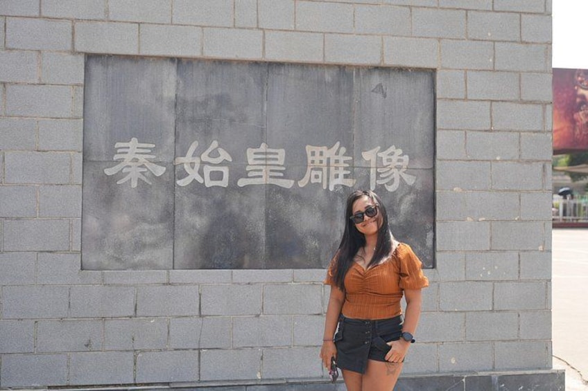 A person standing in front of a sign with Chinese characters. 4