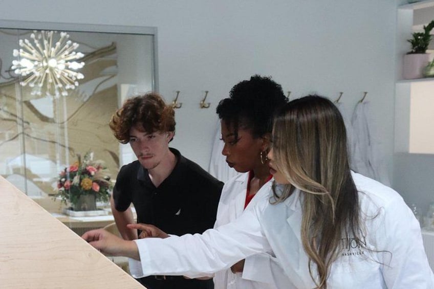 Three people in a modern interior space with a reflective surface and a decorative light fixture. 5