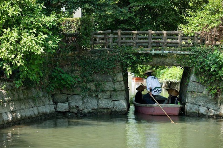 A narrow waterway with a stone wall on one side and a wooden bridge overhead. 4